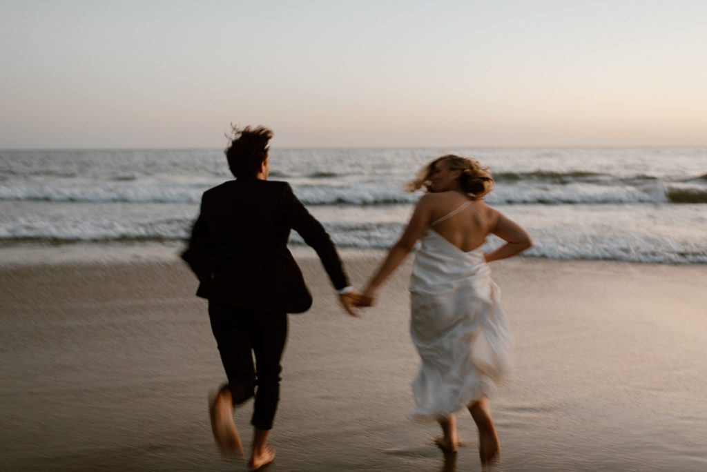 Couple runs holding hands on beach