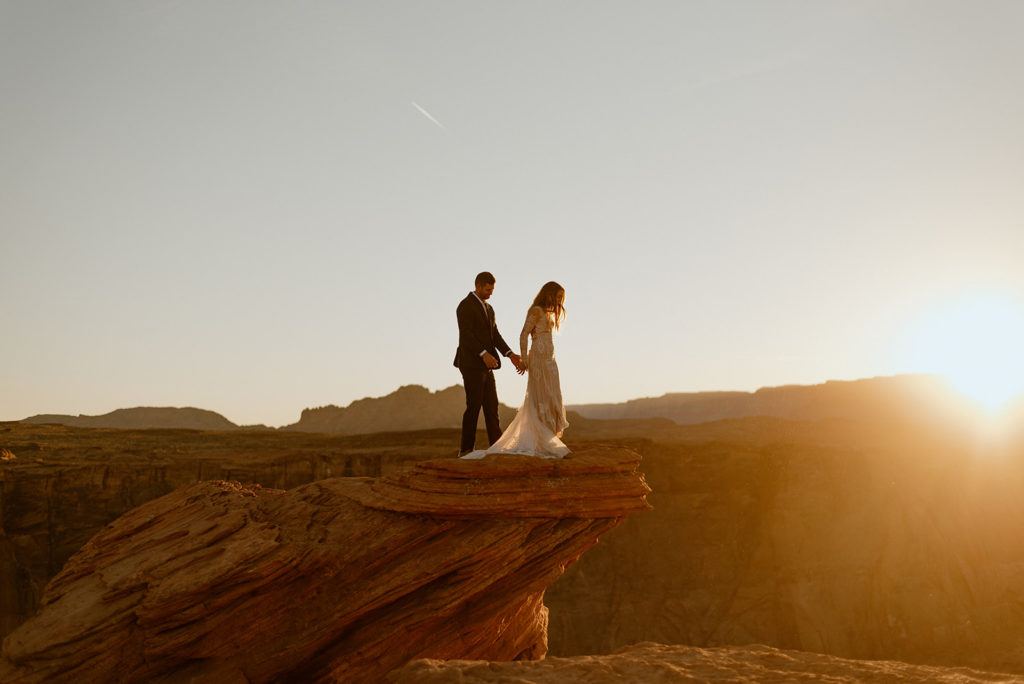 couple stands on ledge at horseshoe bend adventure session