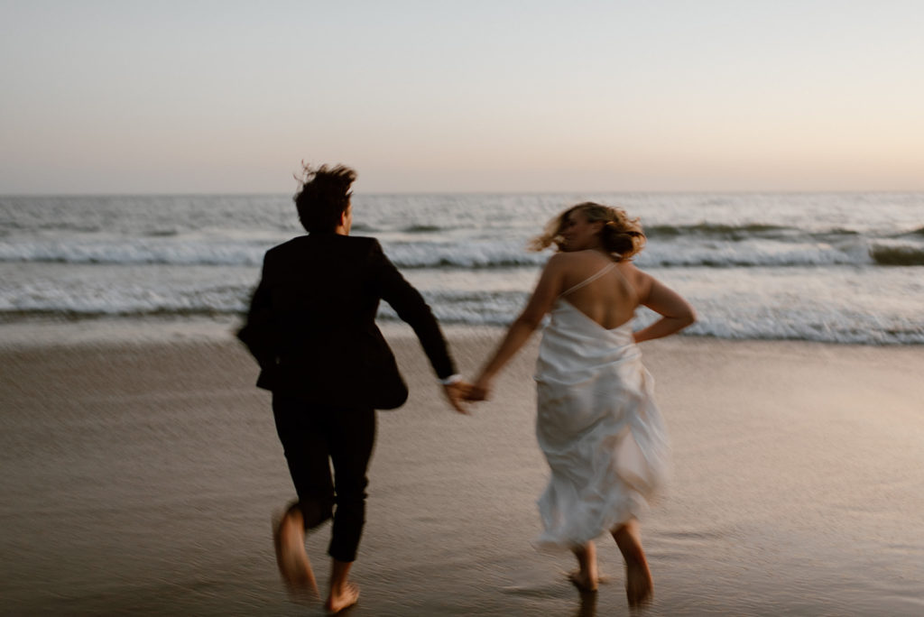 Couple runs holding hands on beach at adventurous elopement