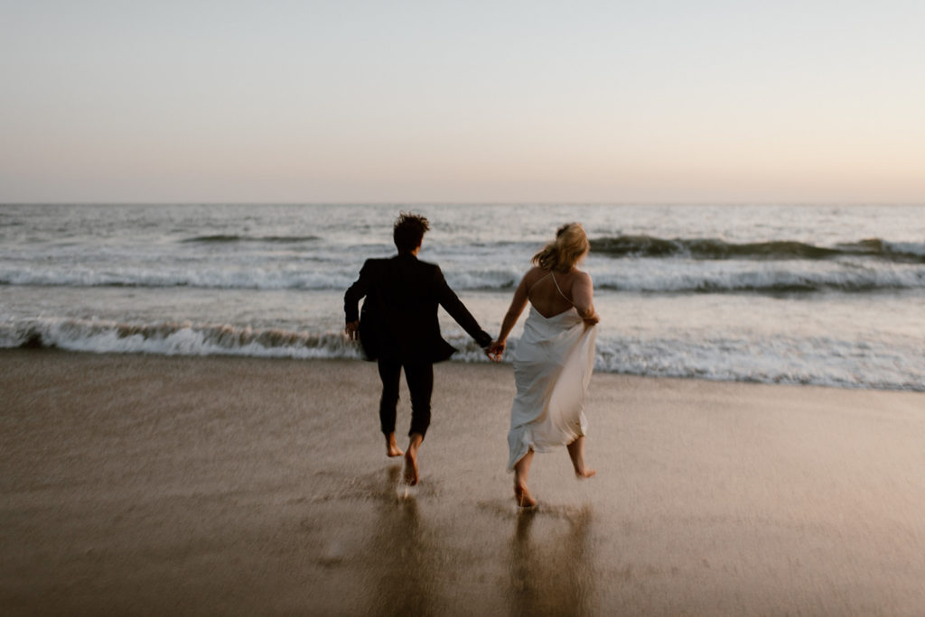 Couple runs holding hands on beach at adventurous elopement