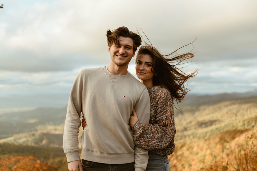 Couple embraces at windy fall engagement session 