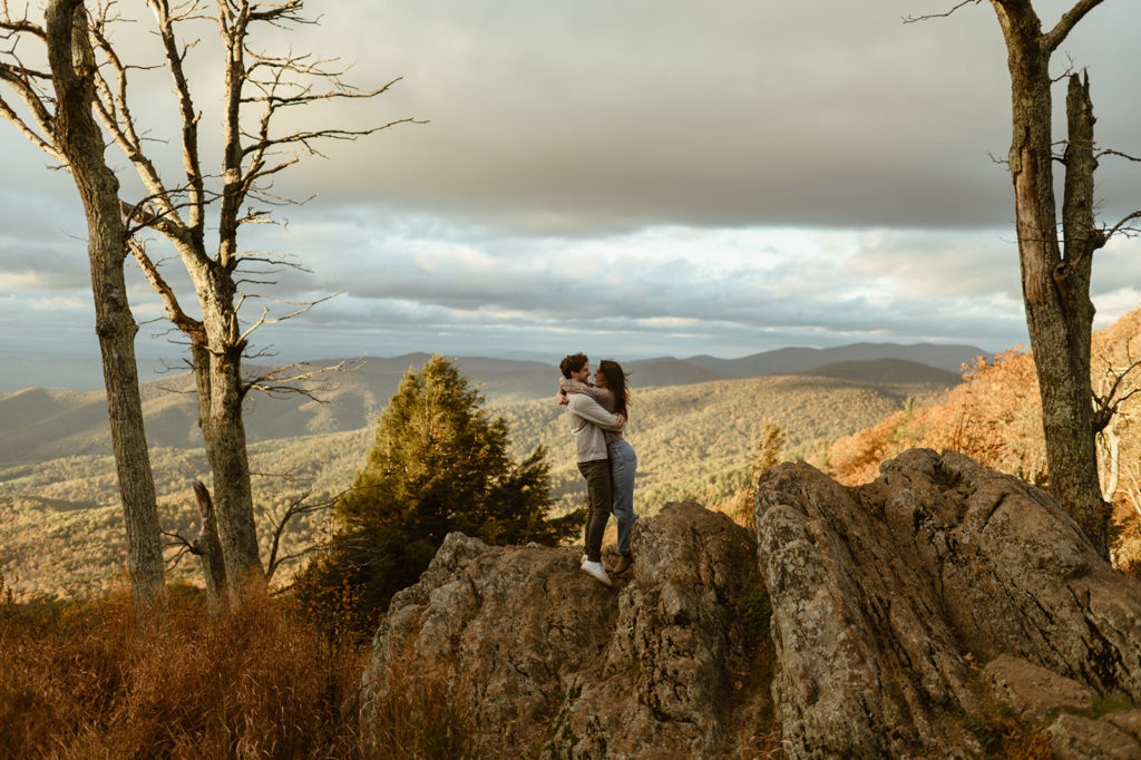 Couple embraces on rocks at windy engagement session