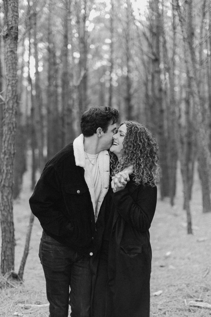 Couple embraces face to face at woods engagement session captured by creative entrepreneur