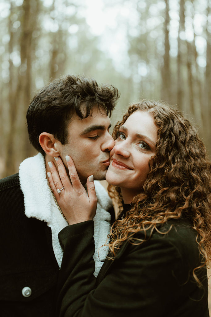 Couple kisses at forest engagement session captured by a creative entrepreneur