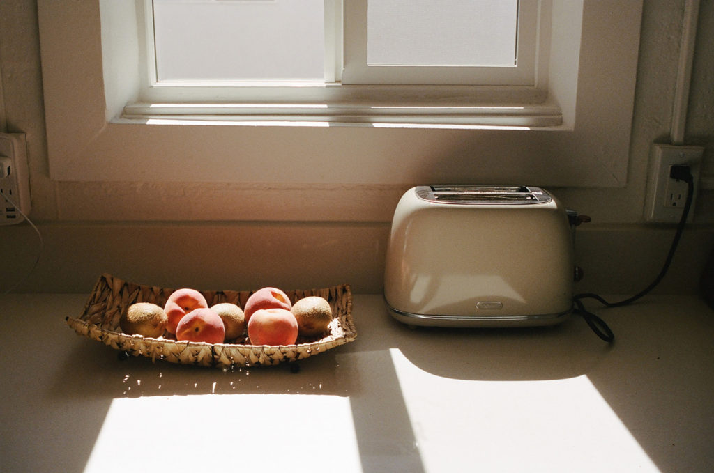 Fruit basket next to toaster in sunlight
