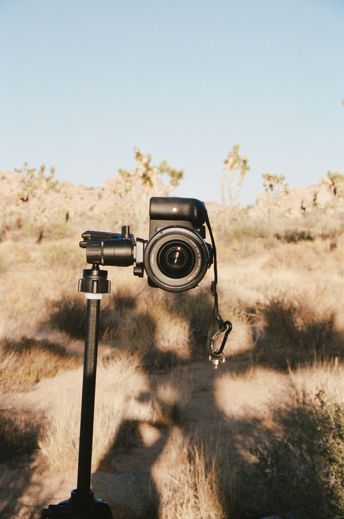 Camera on tripod in desert as photographer compares film photography vs digital