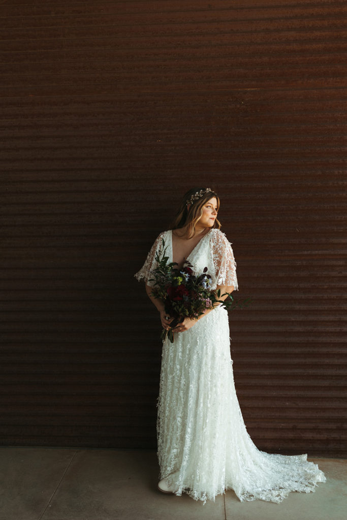 Bride stands holding wedding bouquet