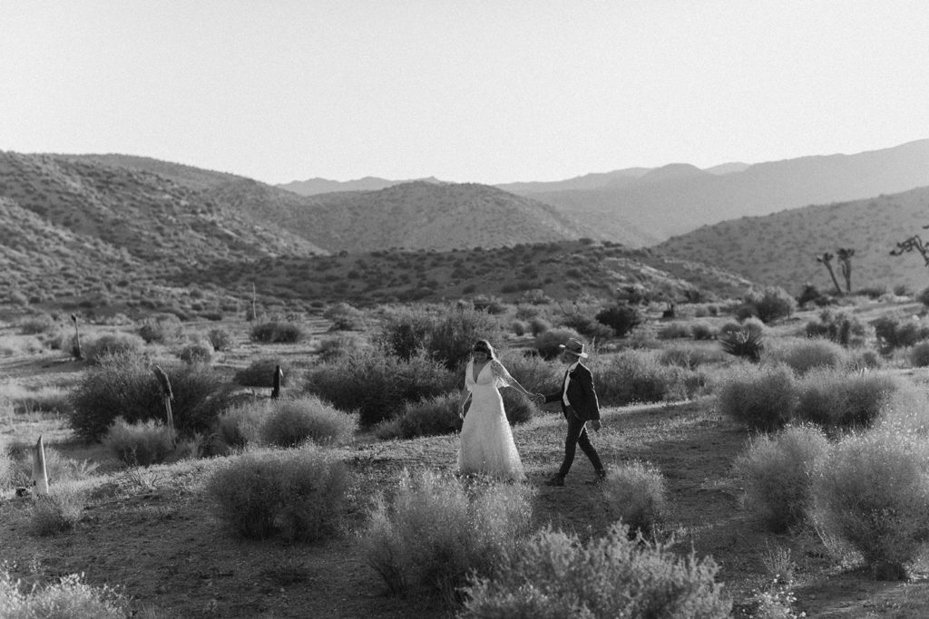 Couple walks holding hands in desert captured by traveling photographer