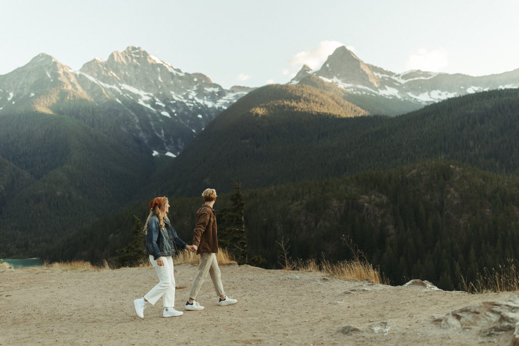 Couple walks holding hands at Cascades mountain engagement shoot