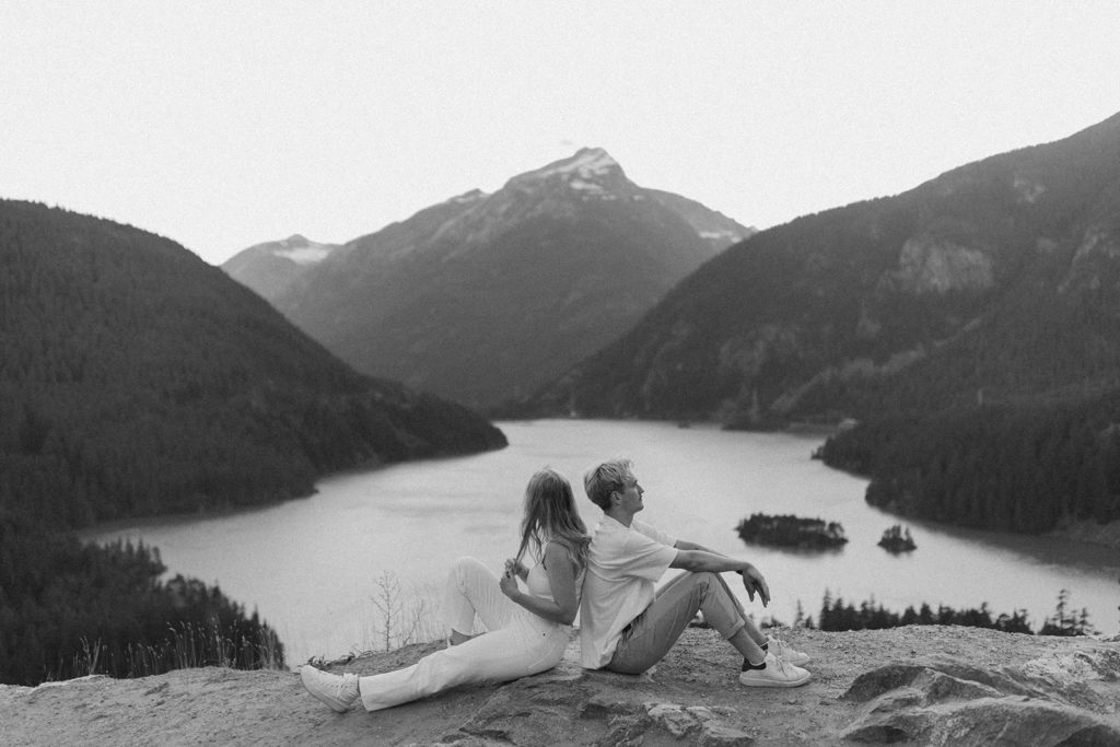 Couple sits back to back at Cascades engagement session