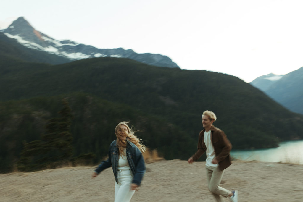 Couple runs in front of Cascades at  mountain engagement session