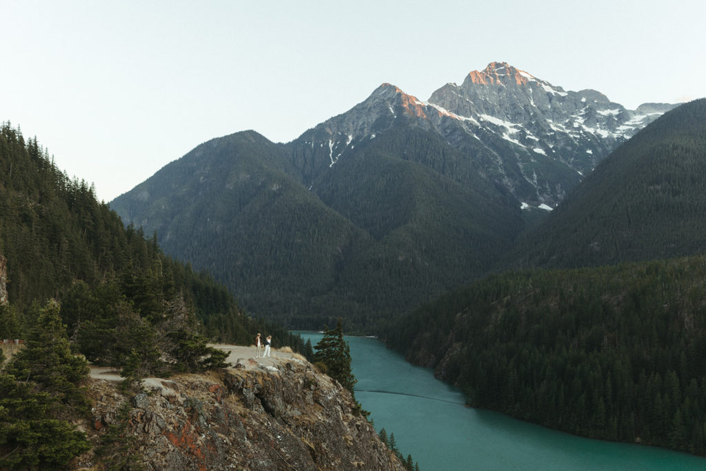 Couple stands at edge of cliff during Cascades mountain elopement