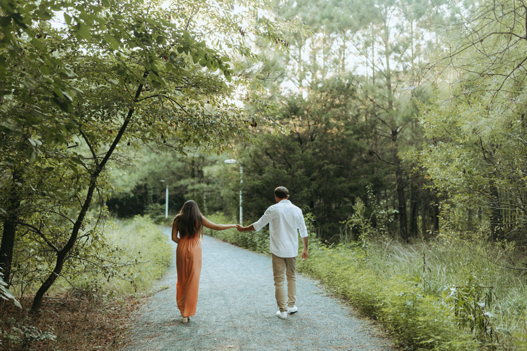 couple walks through forest at Virginia Beach engagement session
