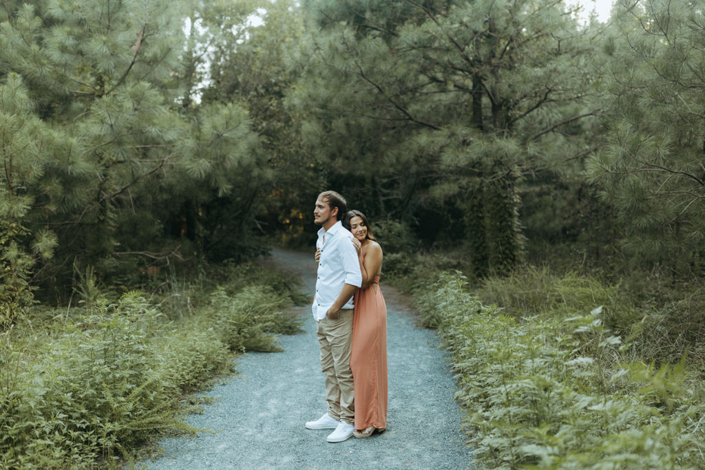 couple embraces at engagement session in forest