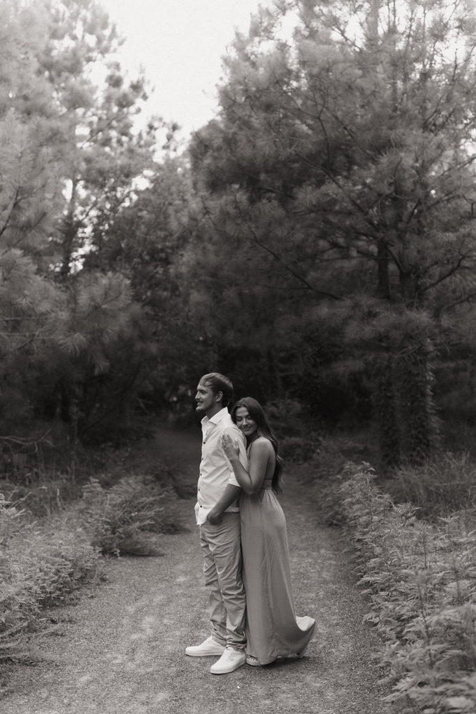 couple embraces at engagement session in forest