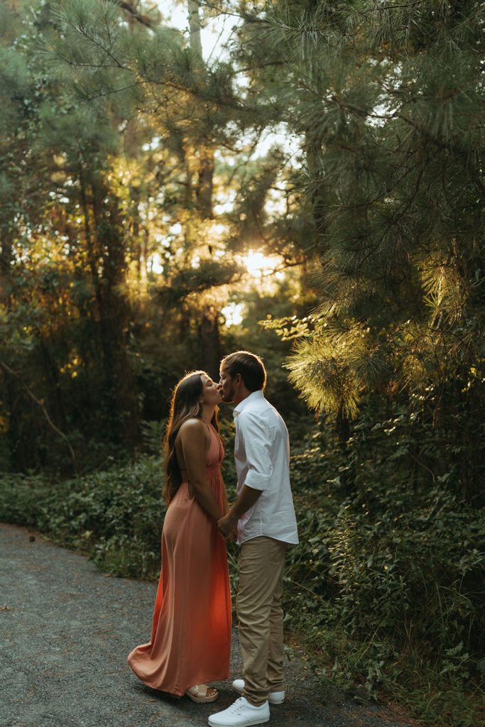 couple kisses in sunset-lit forest trees