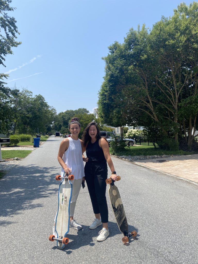 two woman stand together holding longboards in Virginia Beach
