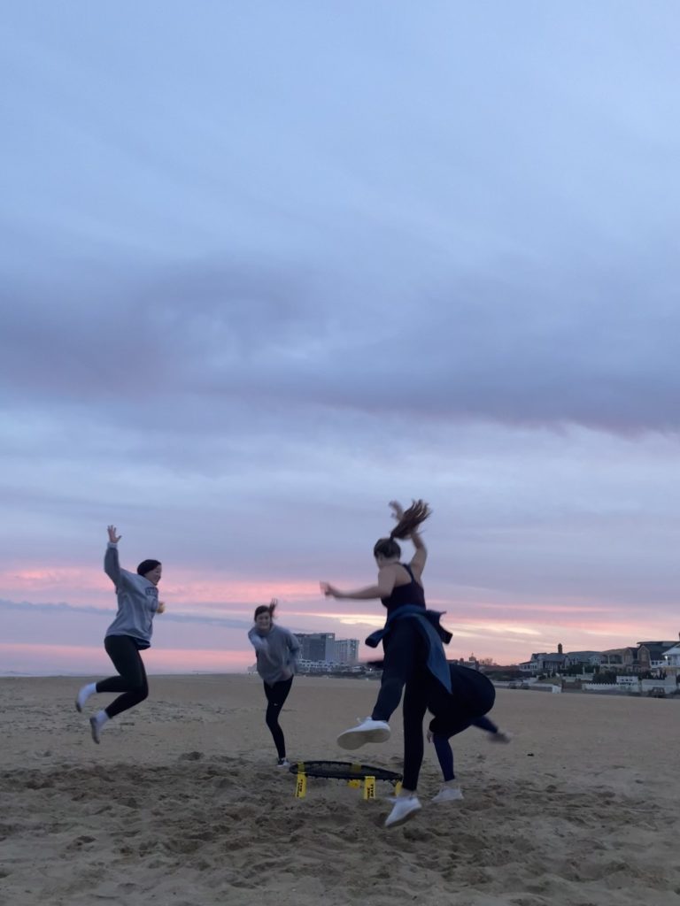 women jump up in the air together on sand at Virginia Beach sunset session