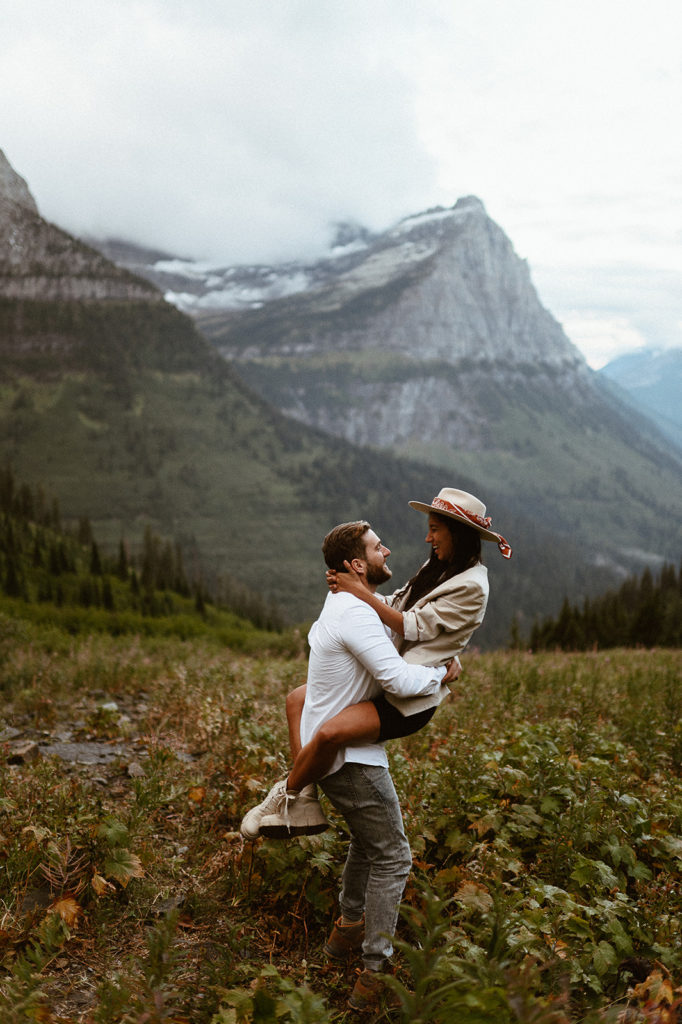 Groom picks up bride in field at Glacier National Park elopement