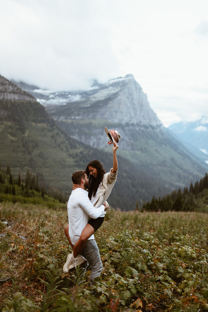 Groom picks up bride in field at Glacier National Park elopement