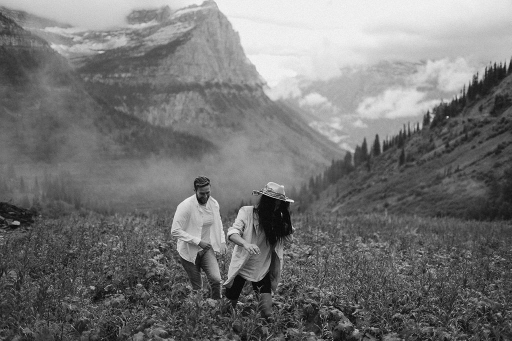 Couple walks through field at Glacier National Park elopement