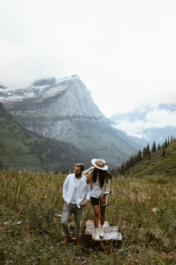 couple stands on rock in front of mountains at Glacier National Park elopement