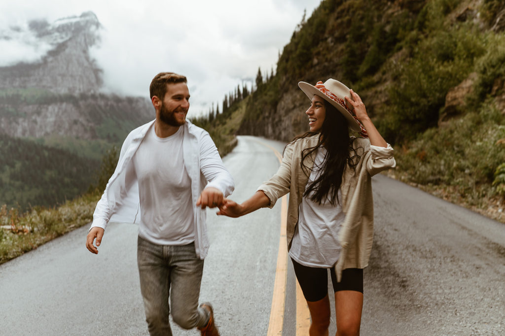 couple runs down street holding hands at Glacier National Park elopement
