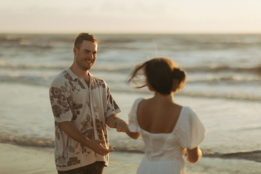 couple twirls at sunrise Virginia Beach engagement session with travel photographer