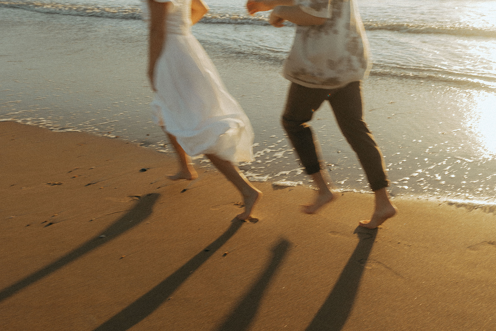 couple runs through ocean water at virginia beach engagement session