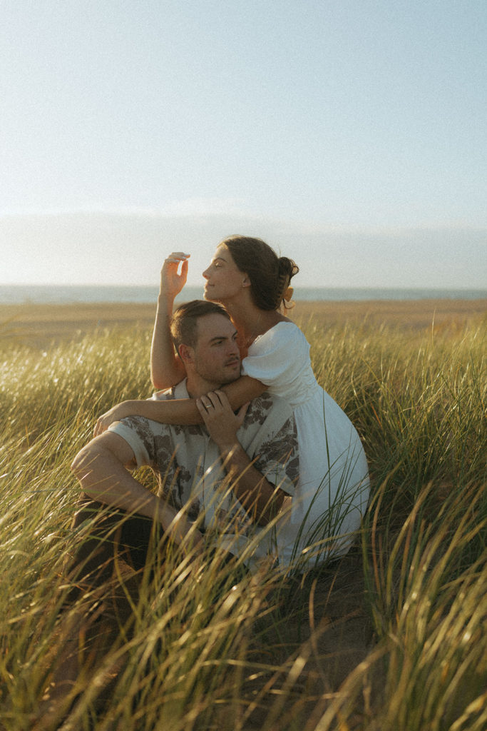 couple embraces in grassy sand dunes at Virginia Beach engagement session 