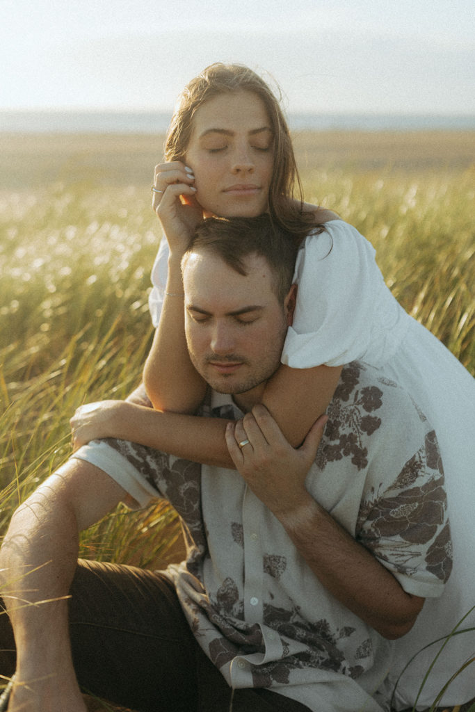 couple embraces in grassy sand dunes at Virginia Beach engagement session 