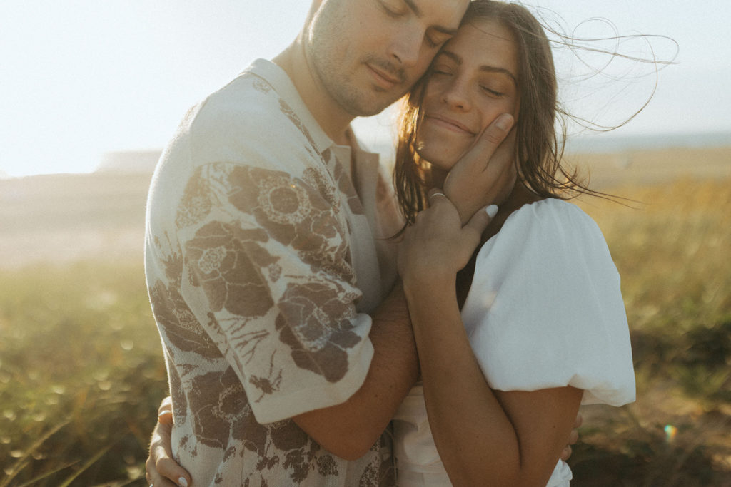 couple embraces in grass at Virginia Beach sand dunes 