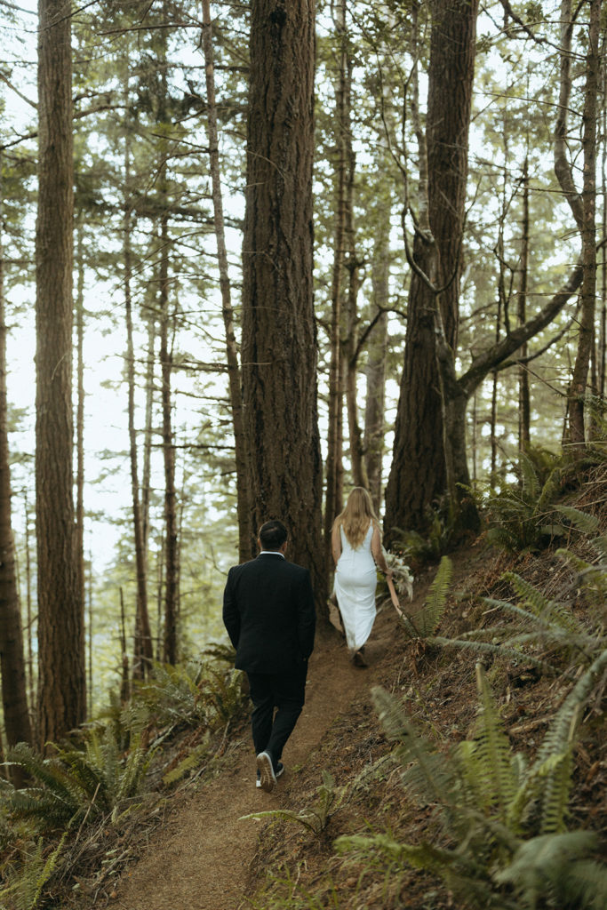 couple walks through woods at Oregon coast wedding photoshoot