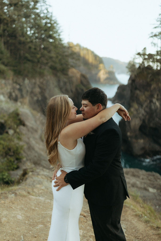 couple embraces on overlook at Oregon coast wedding photoshoot