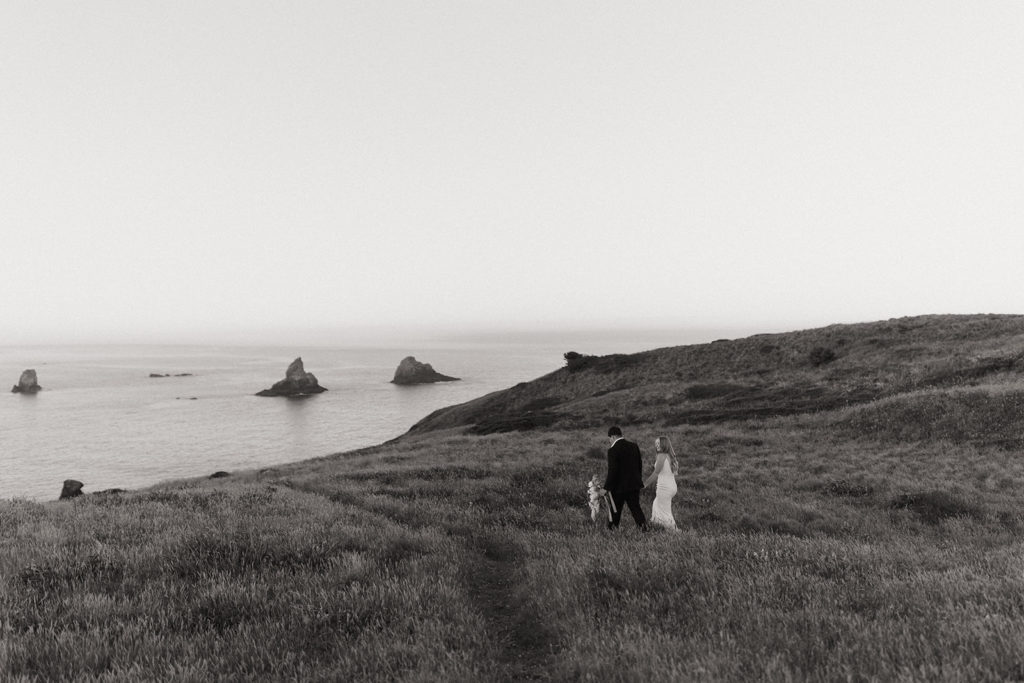 couple walks through field at Oregon Coast elopement 