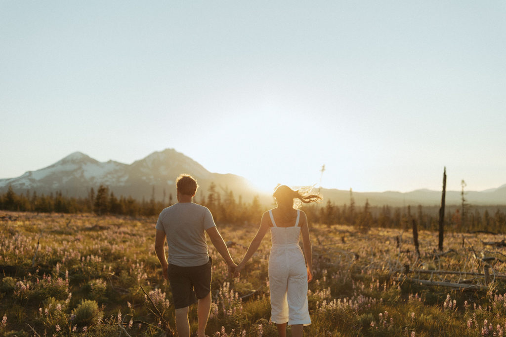 couple walks holding hands at sunset Oregon engagement shoot