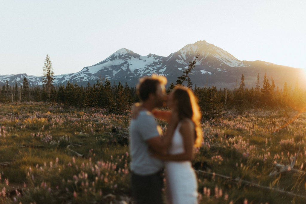 couple kisses in sunset field at engagement session