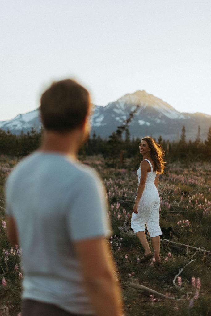 couple walks through field at sunset Oregon engagement shoot