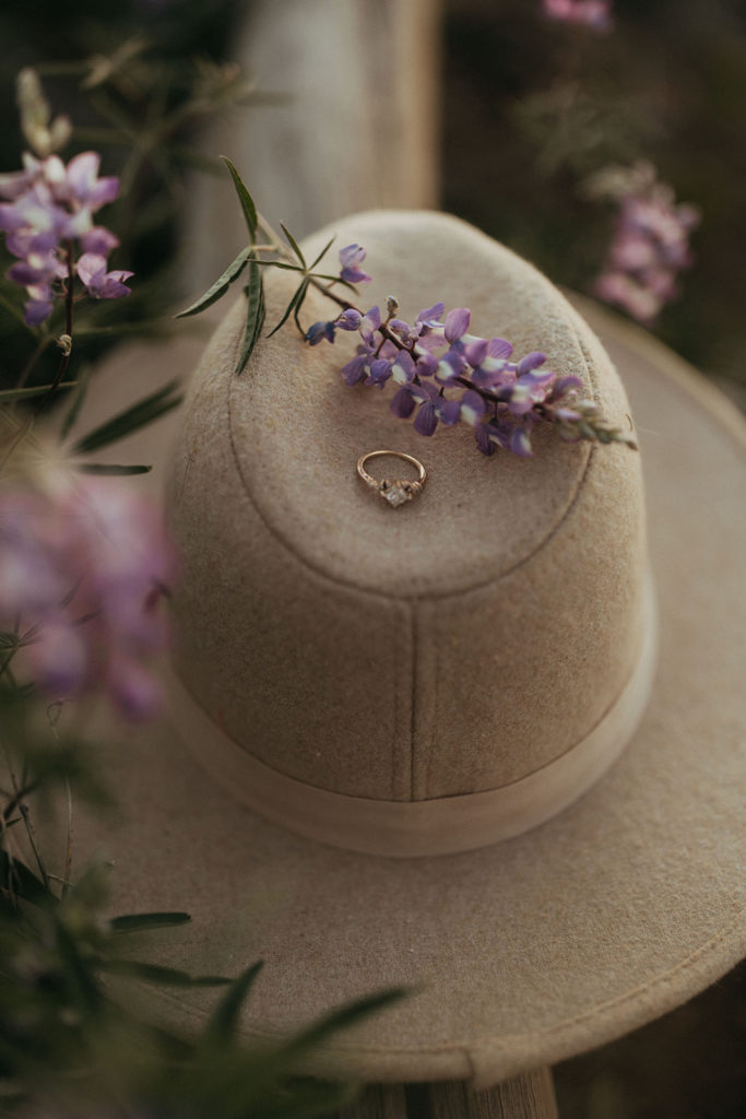 engagement ring placed on hat with flower in field