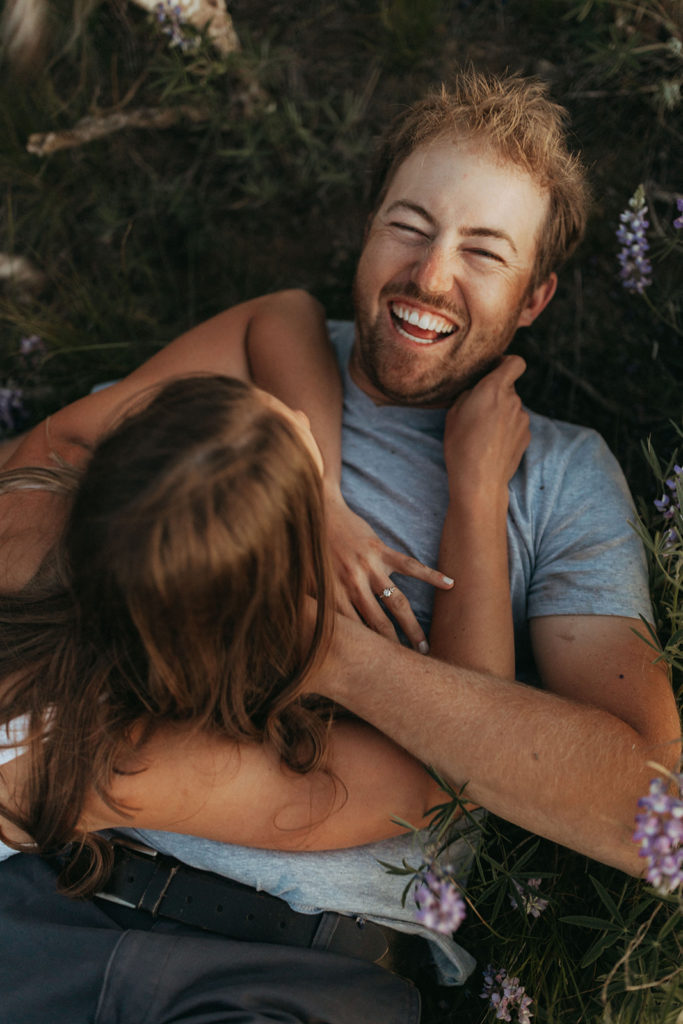couple laughs in flower field at engagement session