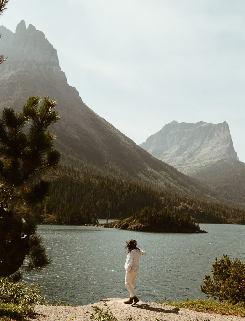 photographer stands at lake by Sun Point Nature Trail at Glacier National Park