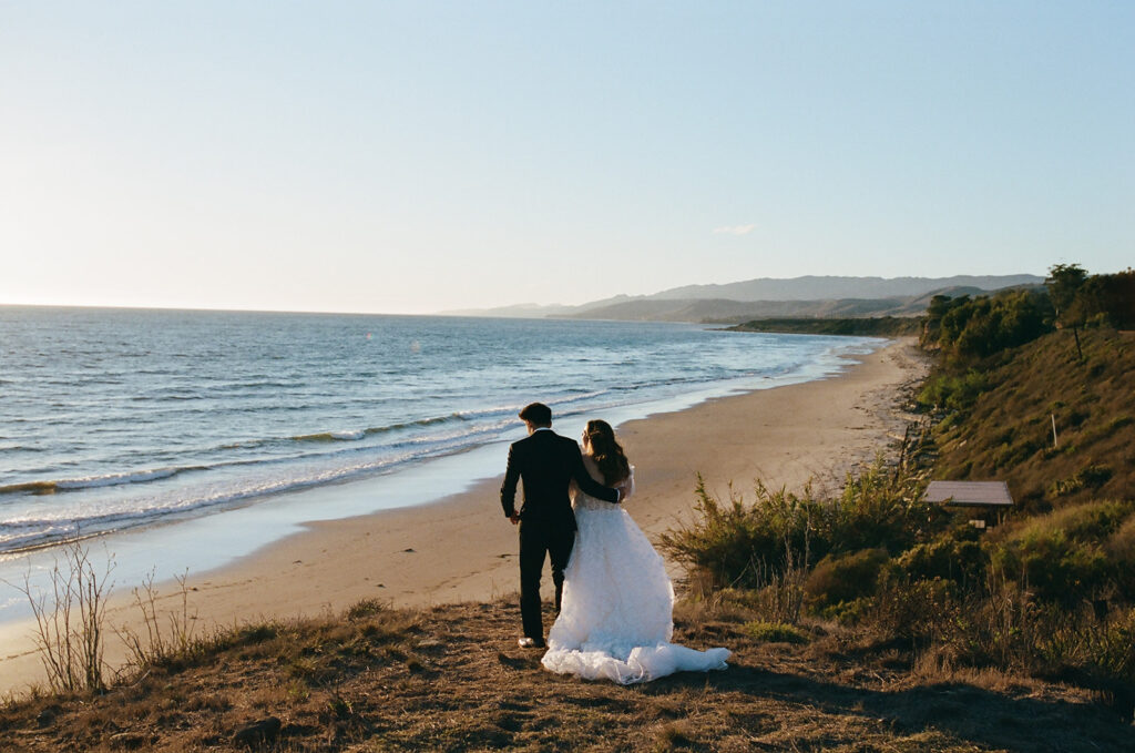 couple embraces on overlook at California coast sunset wedding