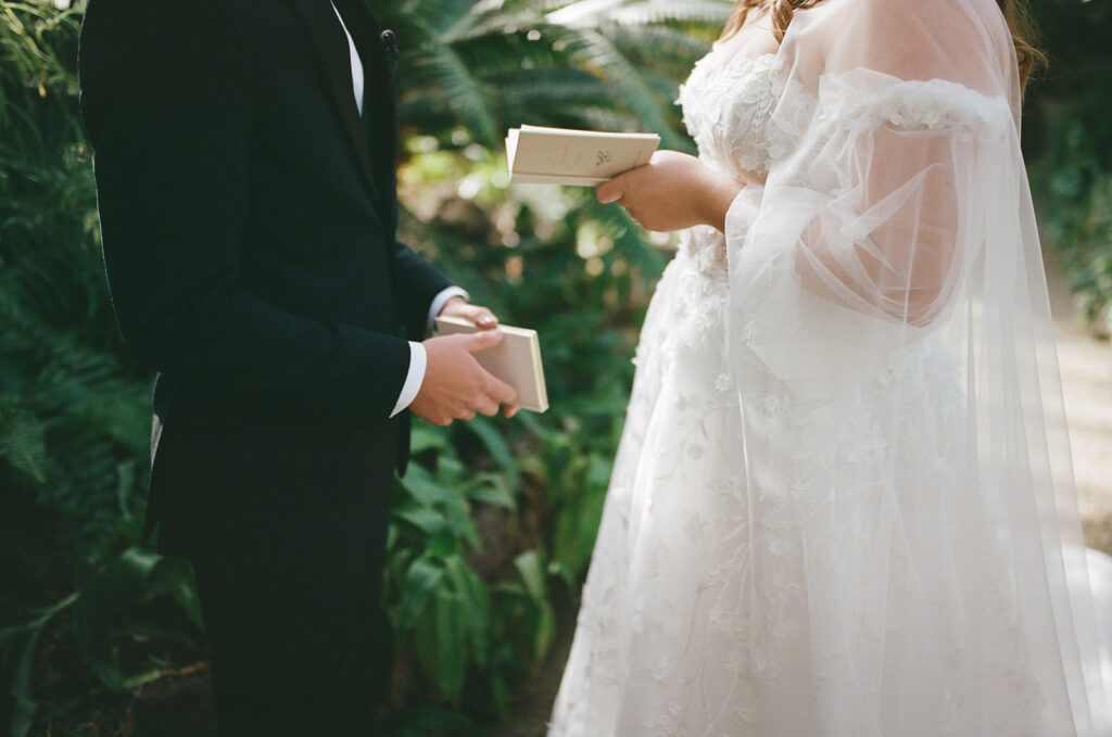 couple holds wedding vow books during first look