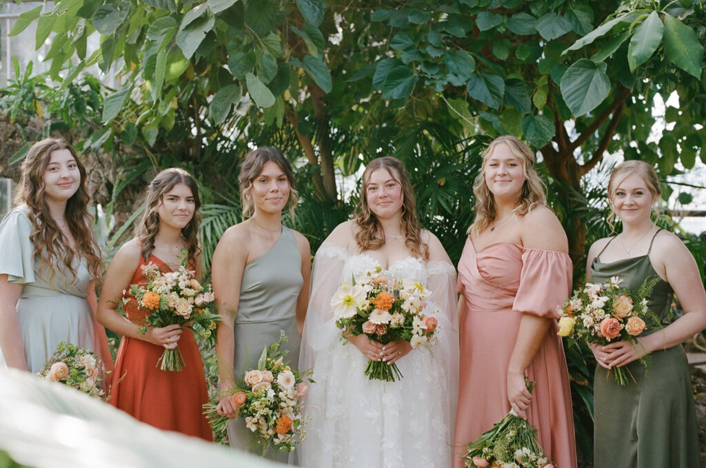 bride stands besides bridesmaids holding wedding bouquets as part of wedding film photography project
