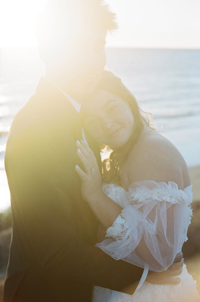 couple embraces at sunset California coast wedding