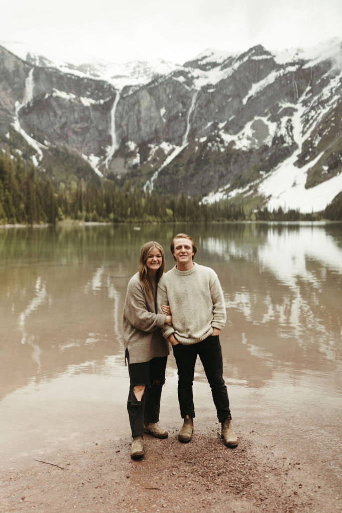 couple stands beside Avalanche Lake at Montana engagement