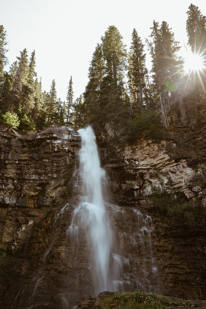 waterfall flows under tree line at Glacier National Park