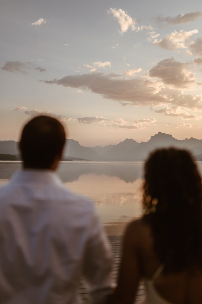couple stands together watching sunset at engagement session