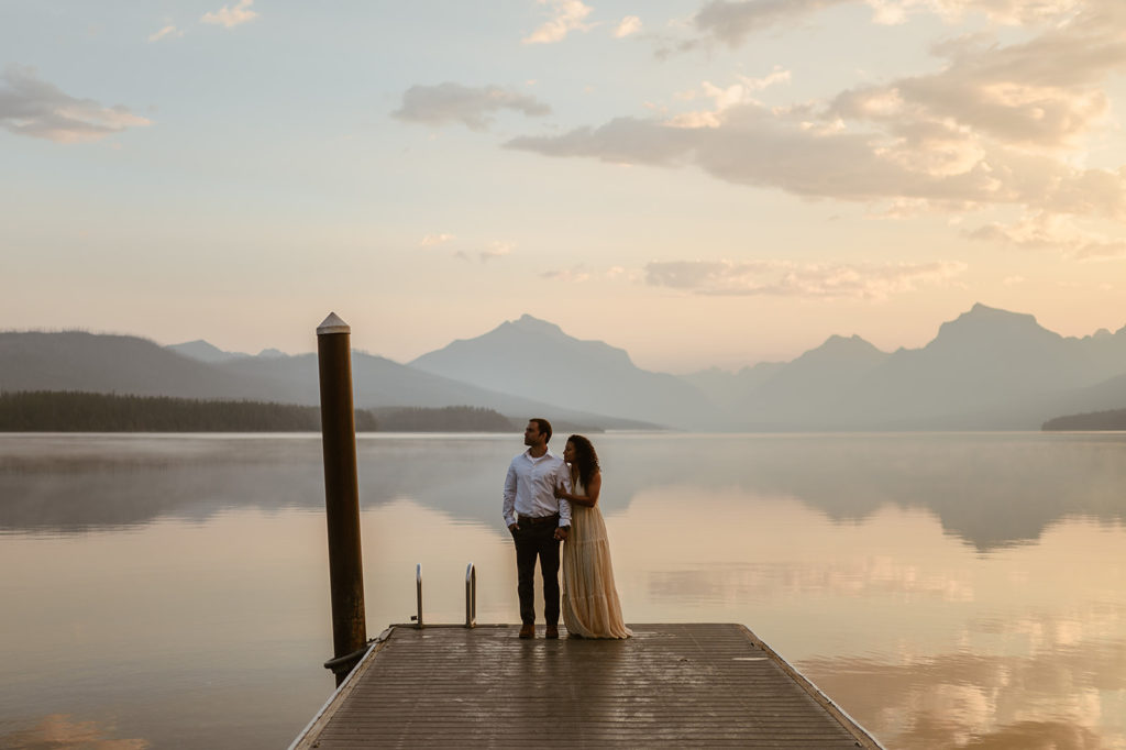 couple stands embracing on pier at sunset engagement session