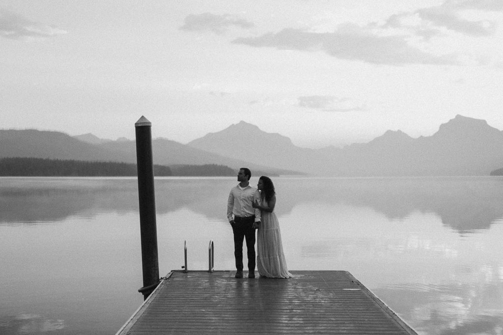 couple stands holding hands on pier at sunset Montana engagement session